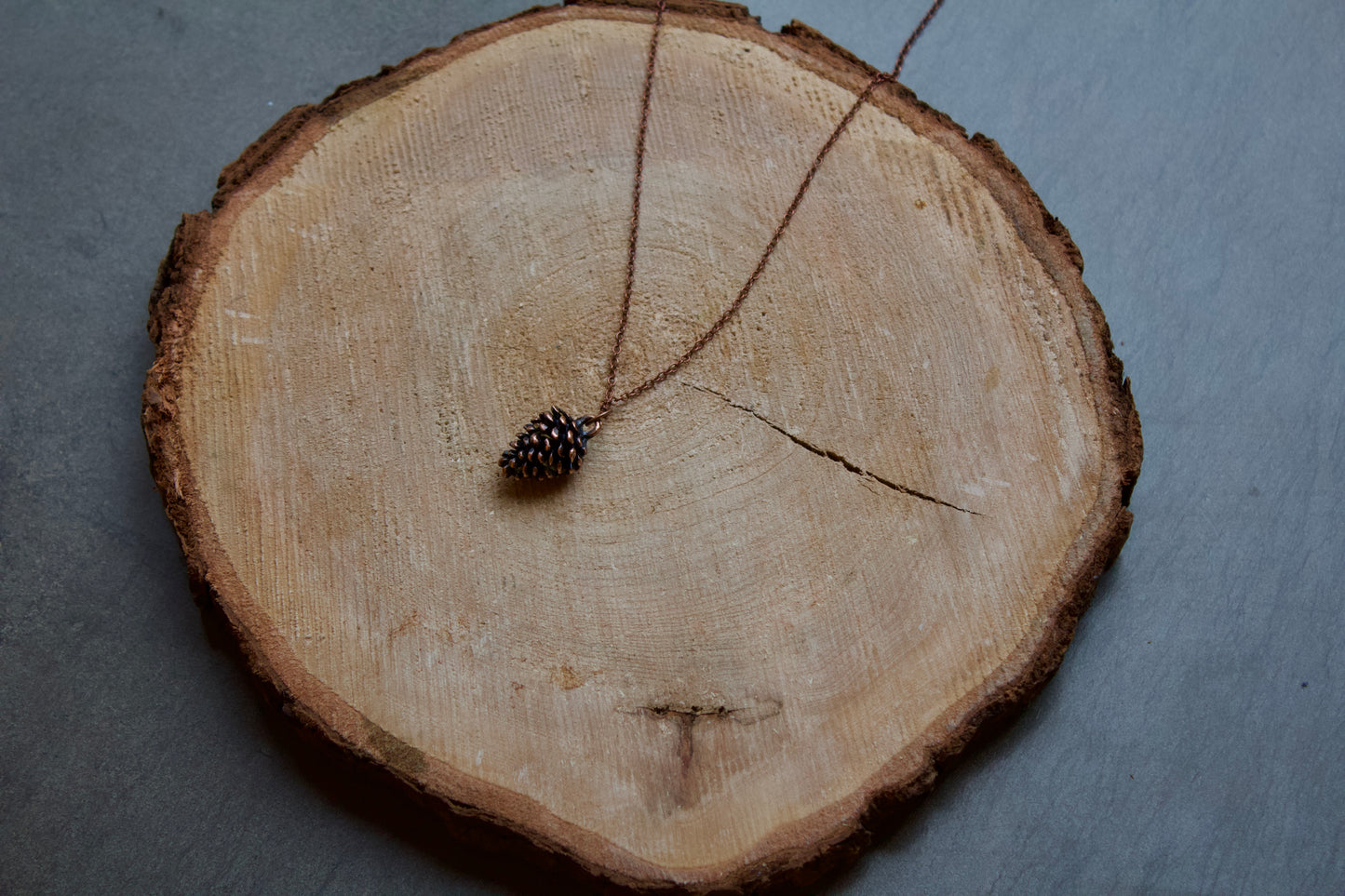 pine cone necklace in stainless steel and brushed with rose gold tones. Pendant is approximately .5" long ,chain is 18" in length lead and nickel free