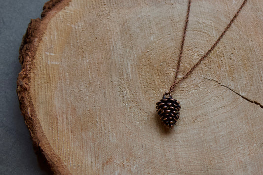 pine cone necklace in stainless steel and brushed with rose gold tones. Pendant is approximately .5" long ,chain is 18" in length lead and nickel free