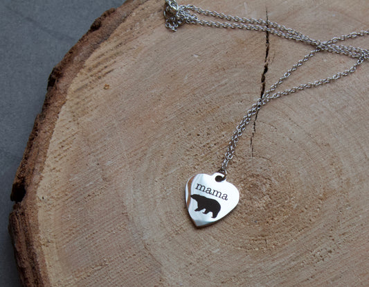 Stainless steel heart shaped necklace with "mama" and a bear embellishments done in black. Necklace is 18" long